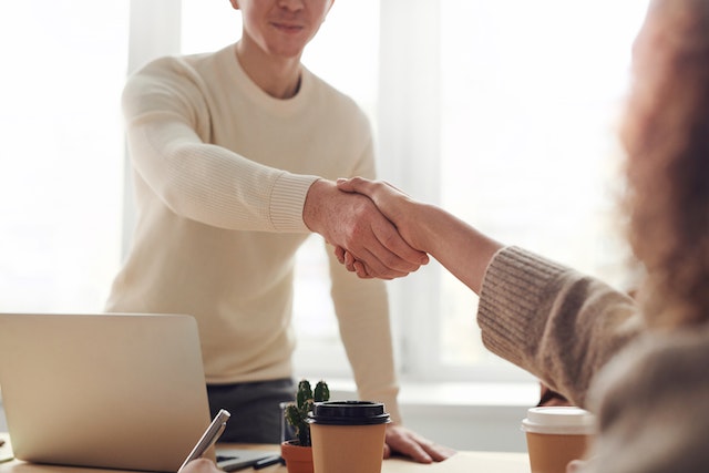 two people shaking hands at desk